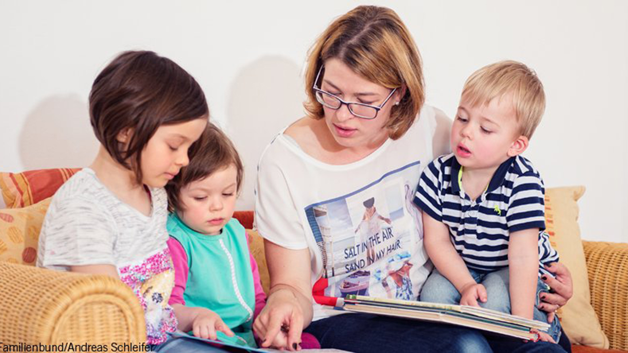 Foto von Frau die 3 Kindern etwas vorliest