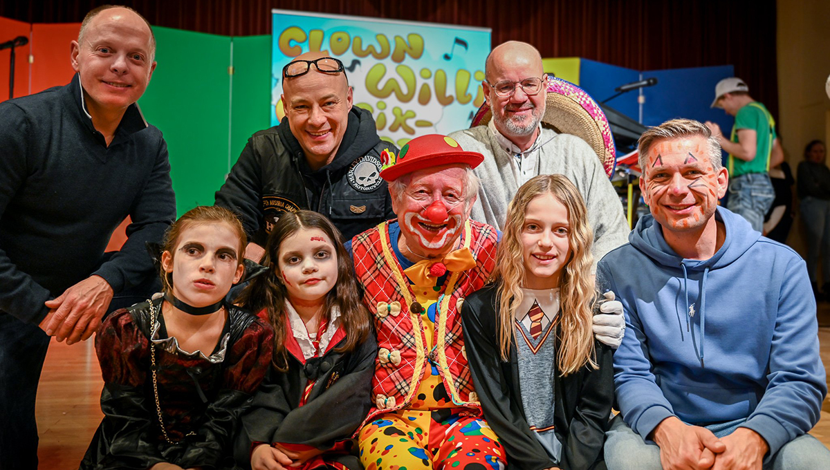 Clown Willi mit verschieden gekleidete Kinder und Erwachsenen