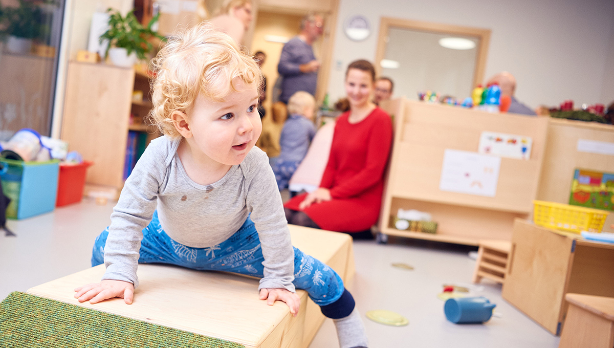 Baby grabbelt in der Energie AG Betreuung herum mit Hintergrund der Aufpasser