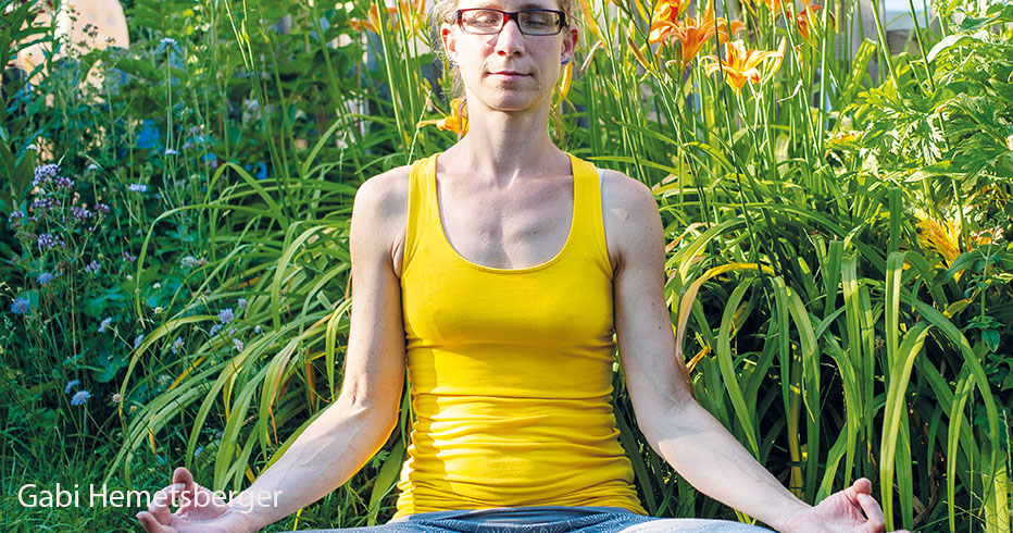 Frau im  Yogasitz im Garten