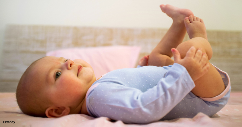 Baby liegt am Boden und hält seine Füßchen