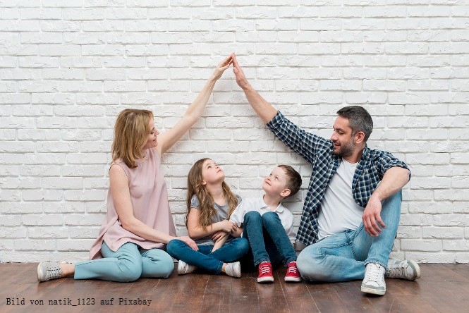 Familie sitzend vor weißer Wand