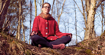 Frau im Schneidersitz im Wald