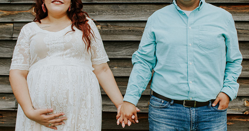 schwangere Frau und Mann stehen Hand in Hand