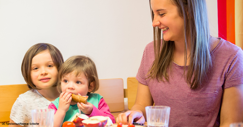 Frau mit 2 Kindern bei Tisch