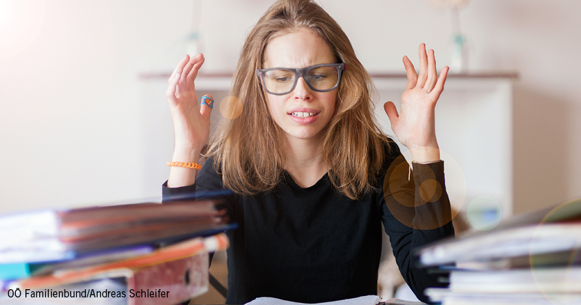 Mädchen mit Schulbüchern das verzweifelt schaut.