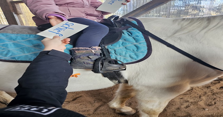 Kind das auf einem Pferd sitzt.