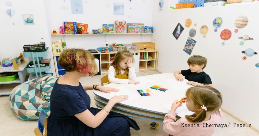 Frau mit Kindern spielend an Tisch