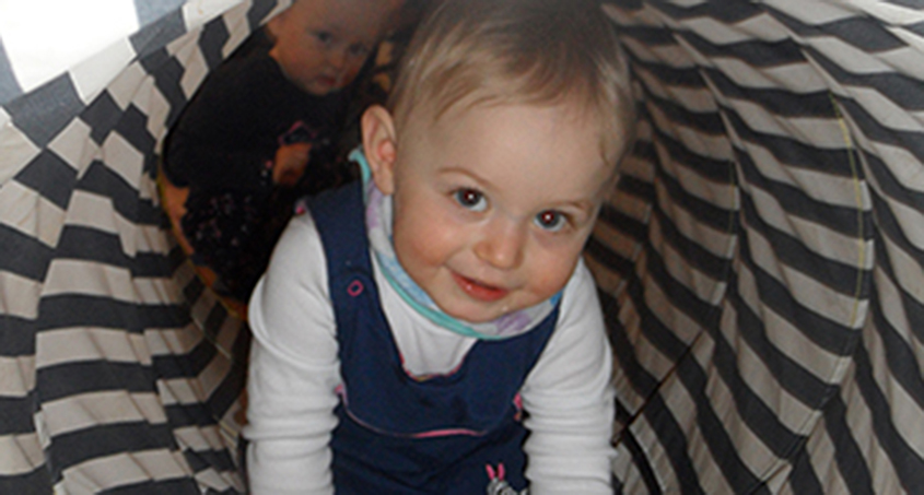 Kleinkind in gestreiften Krabbeltunnel