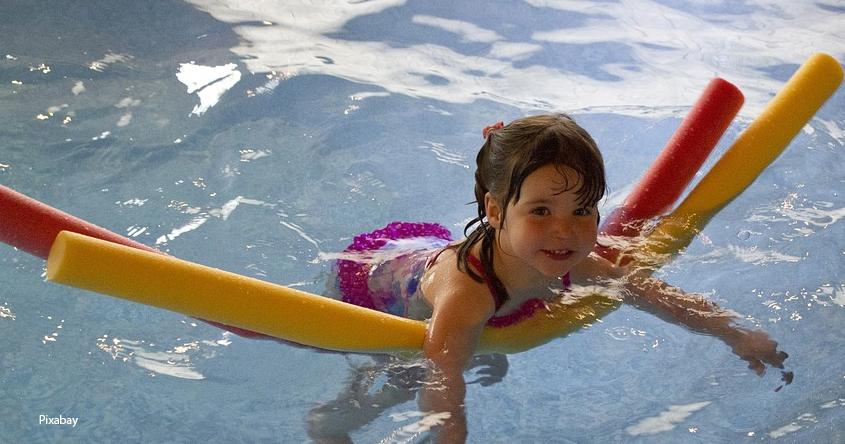Schwimmendes Kind mit zwei Schwimmnudeln