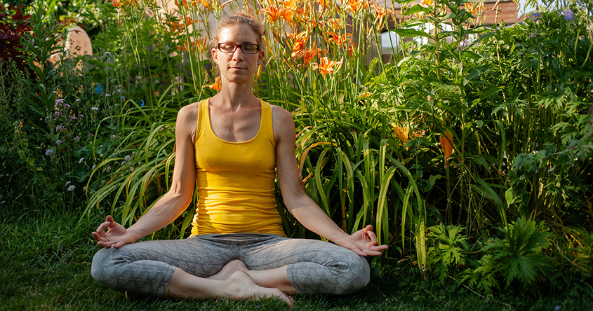Frau im Yogasitz im Garten
