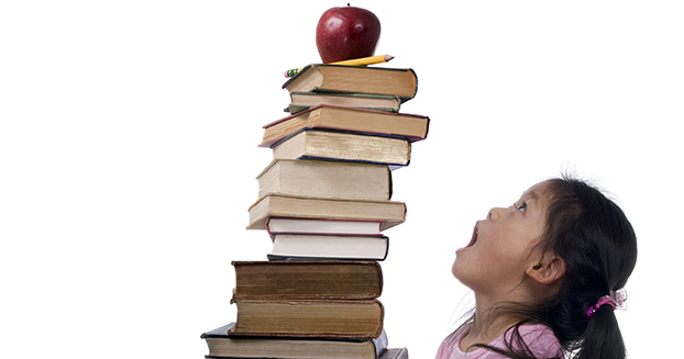Mädchen das einen Stapel Bücher trägt.