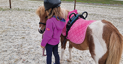 ein Kinder das ein Pferd am Zügel hält