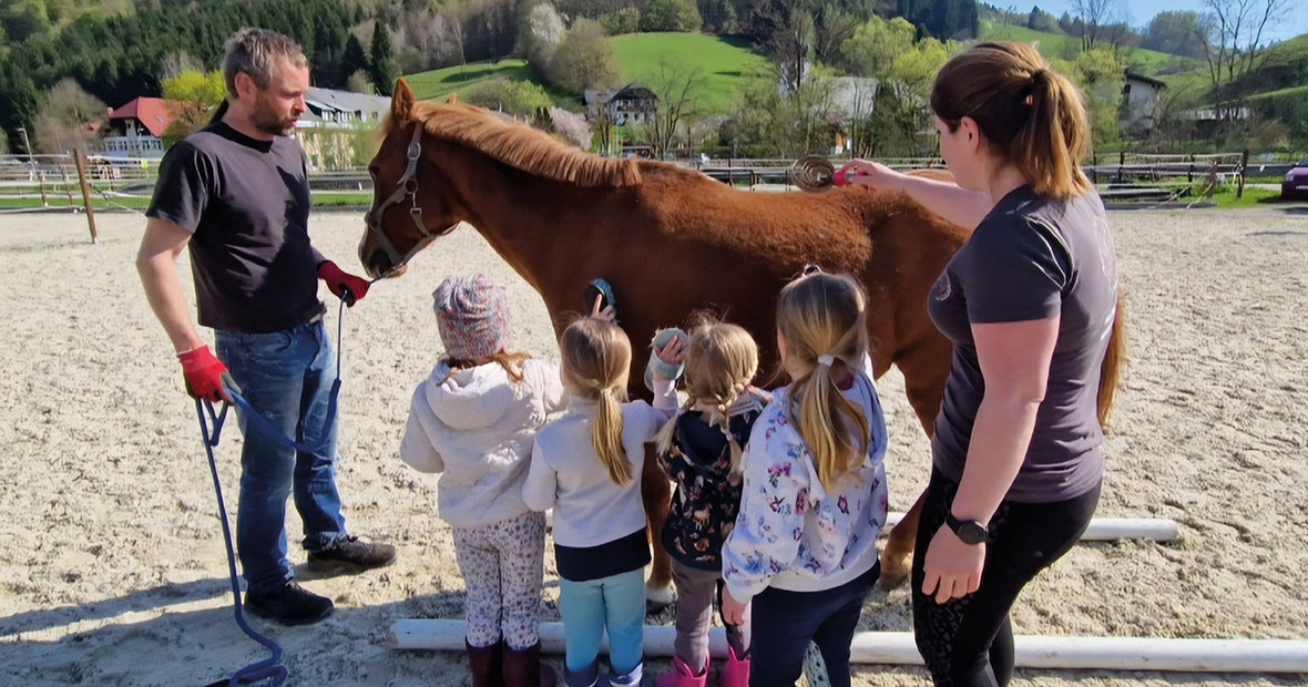 Einige Kinder und eine Frau vor einem Pferd, das ein Man am Zügel hält