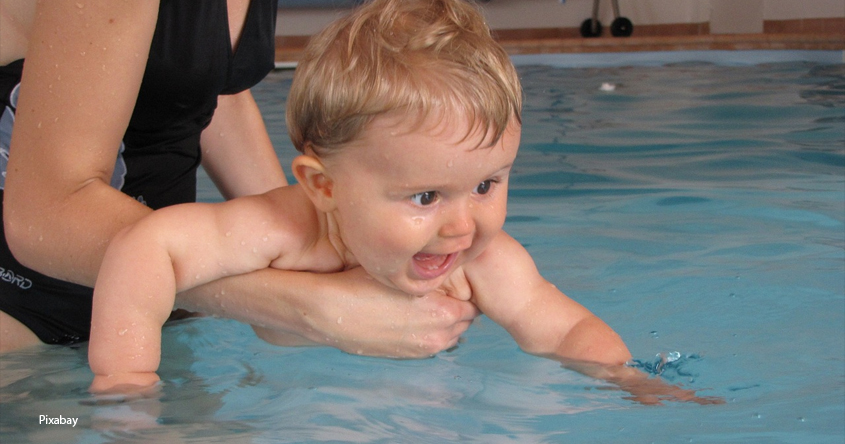 Baby im Wasser gehalten von einer Hand
